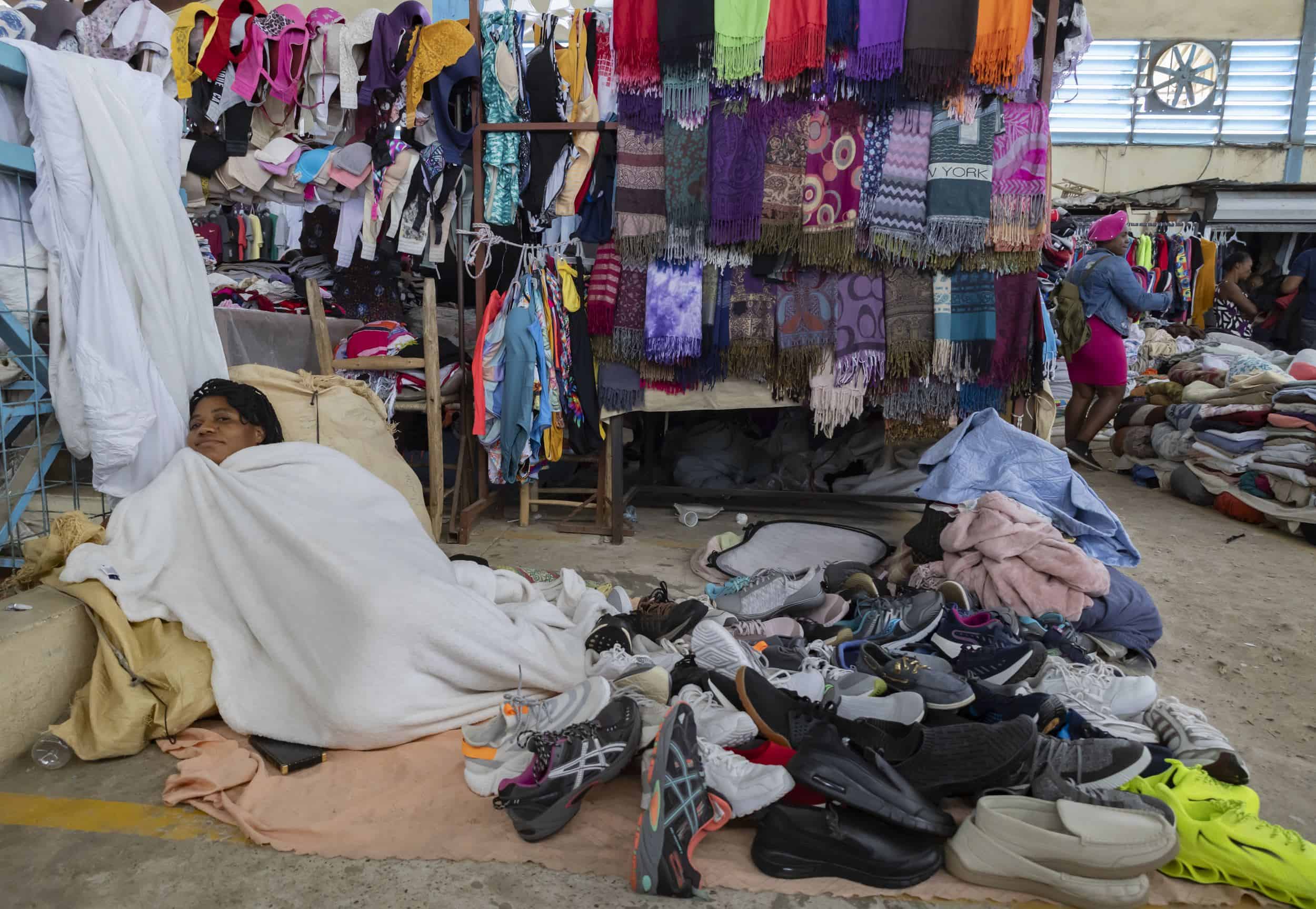 Una mujer, en la planta de arriba del edificio, descansa envuelta en una manta.