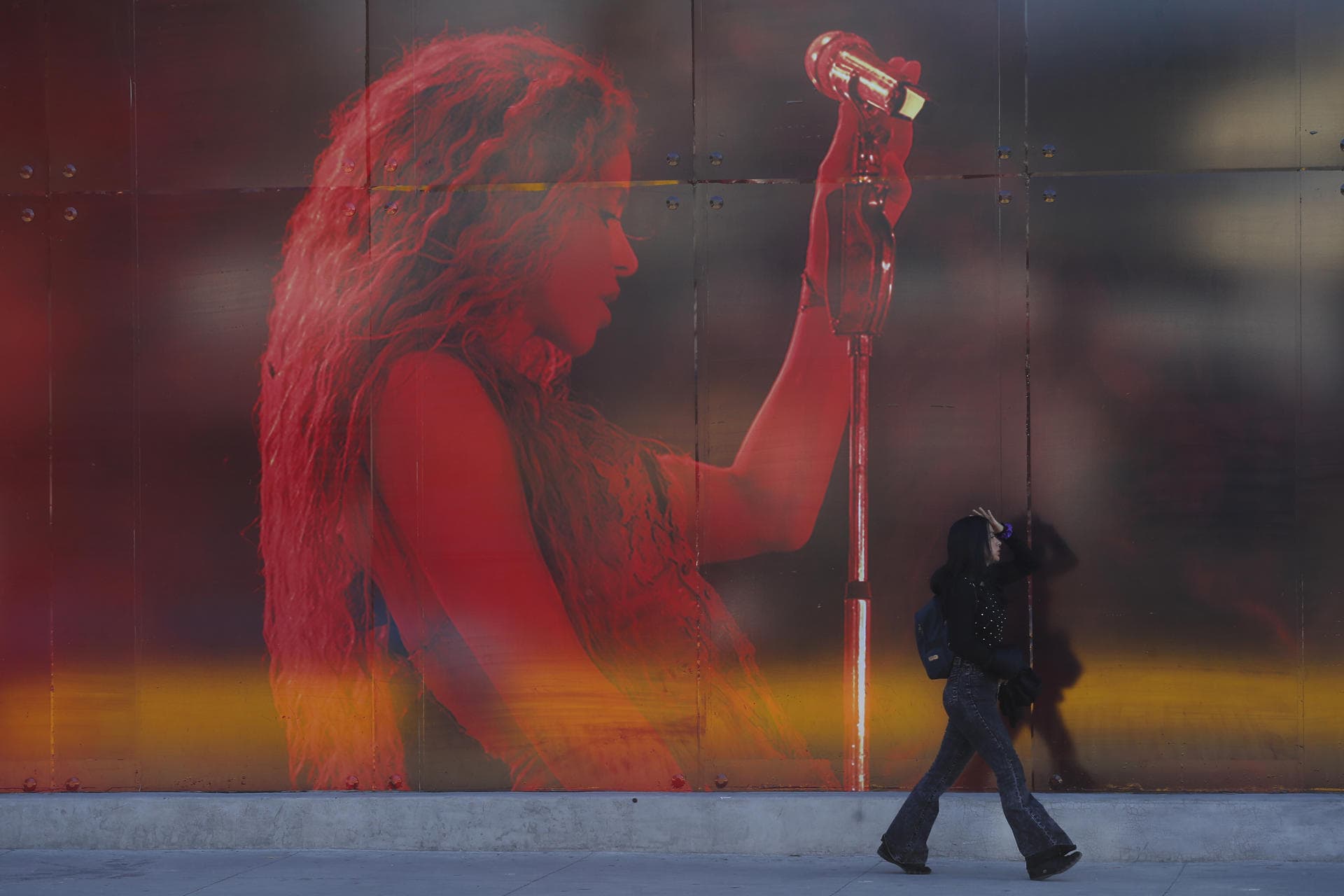 Una mujer camina frente a un aviso publicitario que anuncia el concierto de la cantante colombiana Shakira en el Estadio Jorge El Mágico González este jueves, en San Salvador (El Salvador).