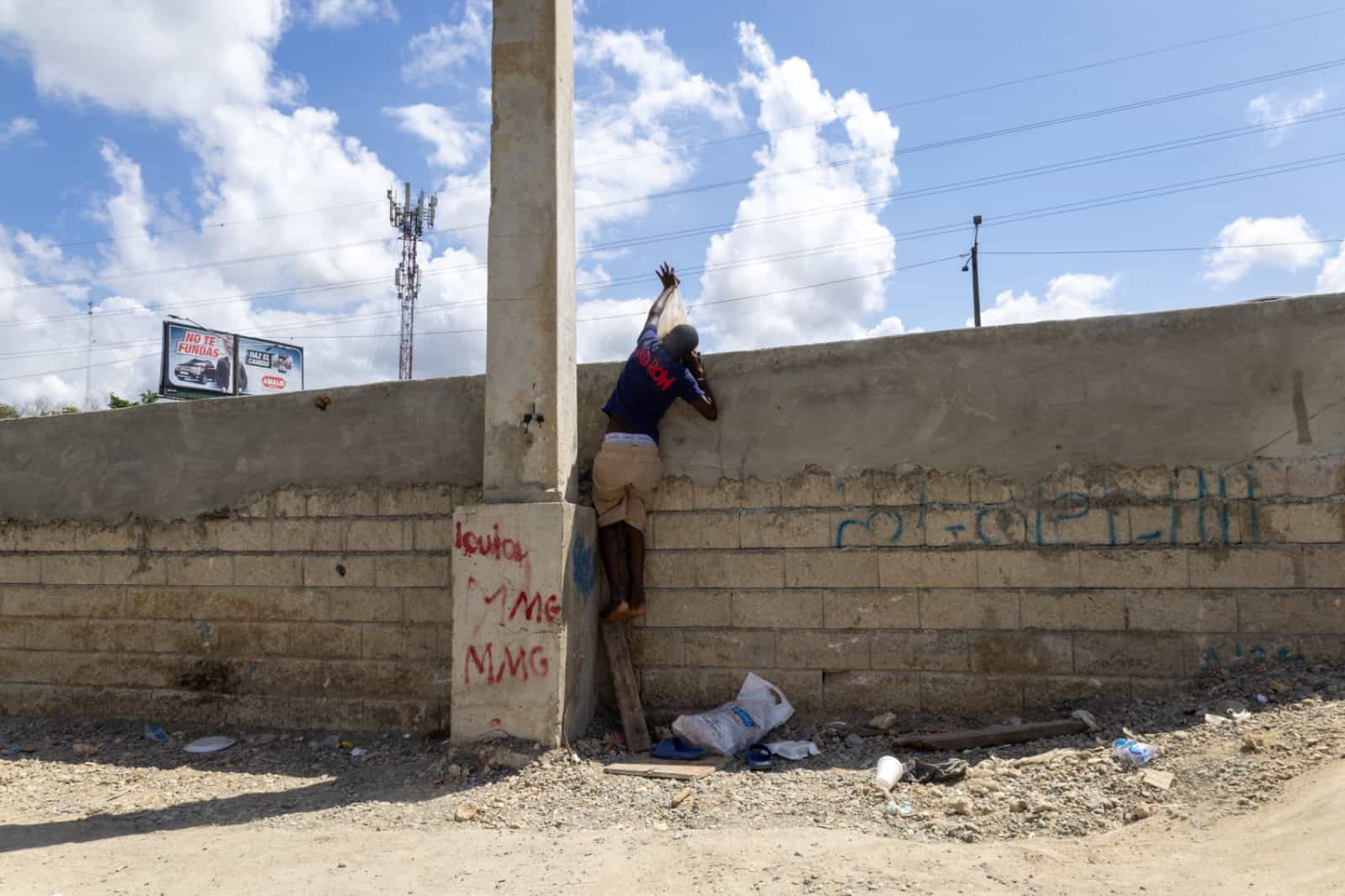Niño intenta subir a la acera con fundas de basura ante la falta de accesos adecuados.