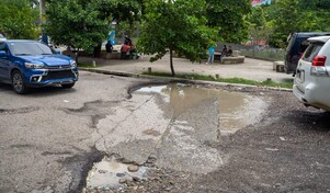 Entre hoyos y agua acumulada: así transitan conductores y peatones por calles del Gran Santo Domingo