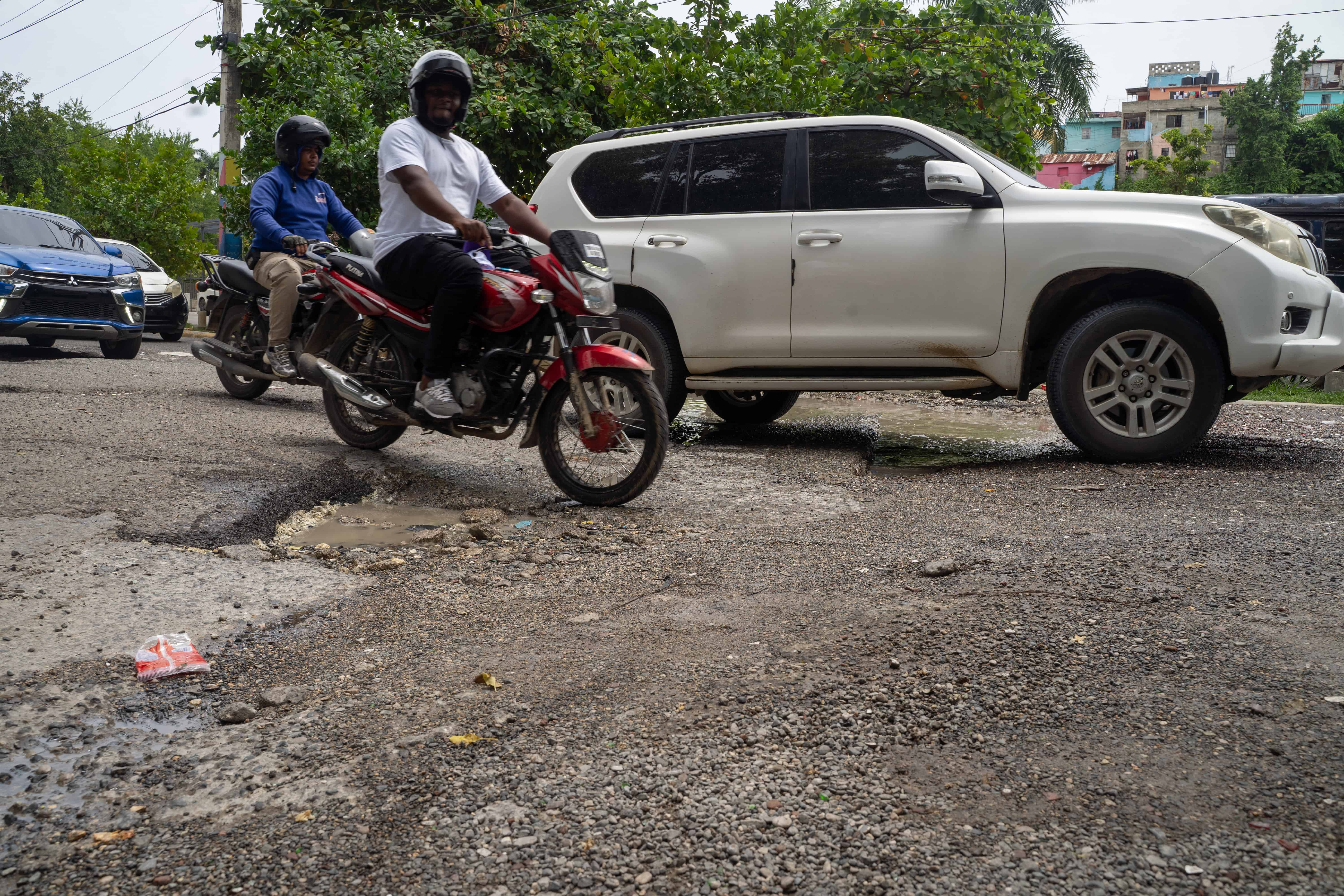 El deterioro del pavimento afecta la circulación frente al Cristo Park, donde vehículos y motocicletas deben esquivar los baches.