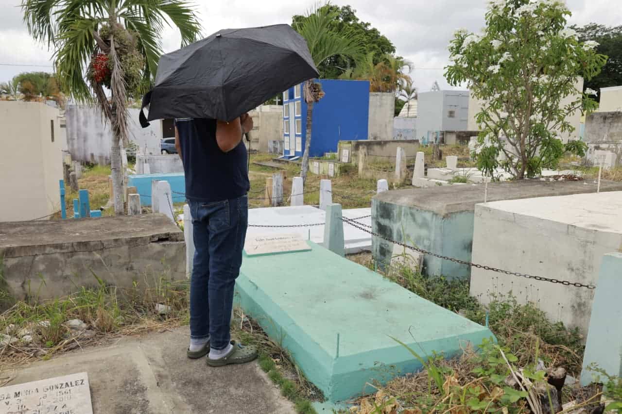 Un hombre permanece de pie frente a la tumba de un familiar en el cementerio Cristo Redentor.