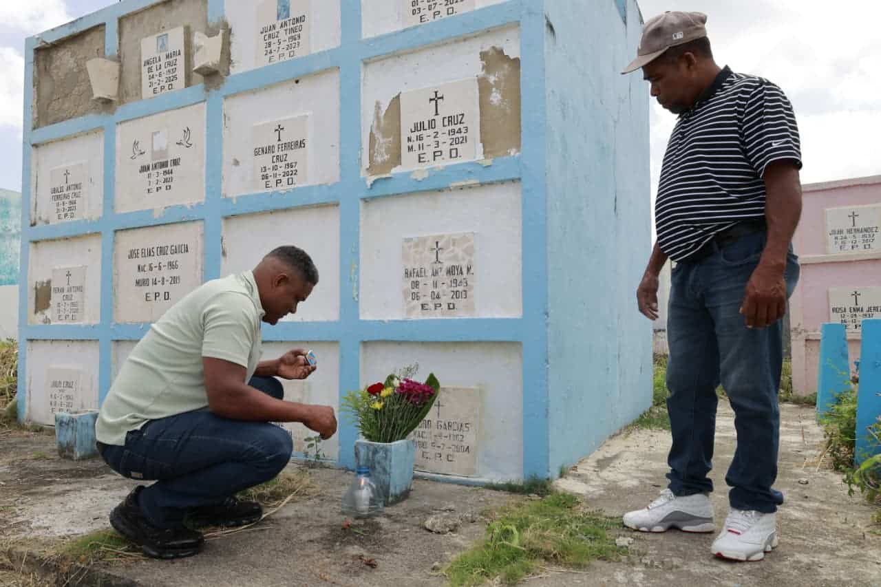 Hombres observan la tumba de un ser querido durante su visita al cementerio Cristo Redentor.