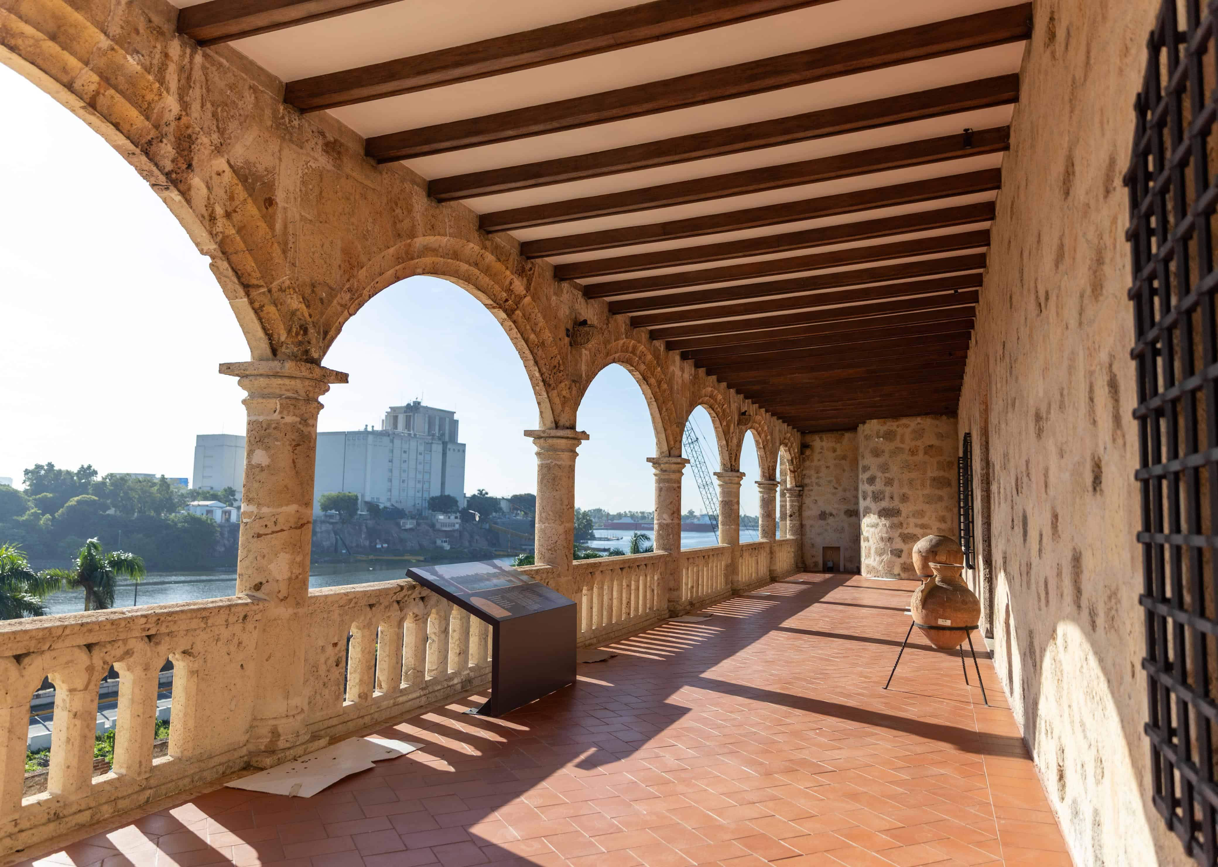 Vista exterior del corredor superior porticado del palacio, caracterizado por sus arcos de medio punto en piedra coralina y su vista panorámica hacia el río Ozama.