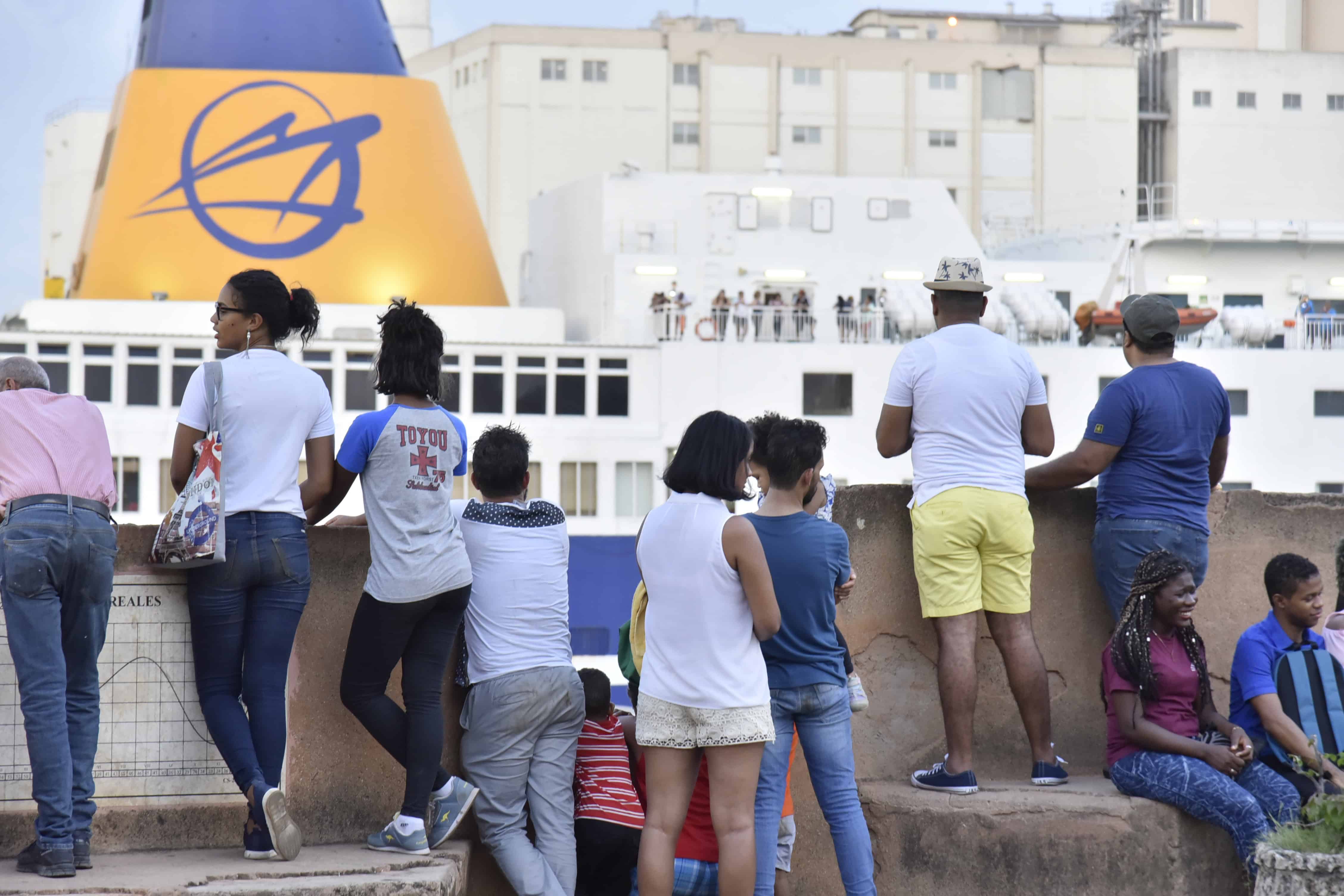 Un grupo de personas observa la llegada del ferry en el río Ozama.