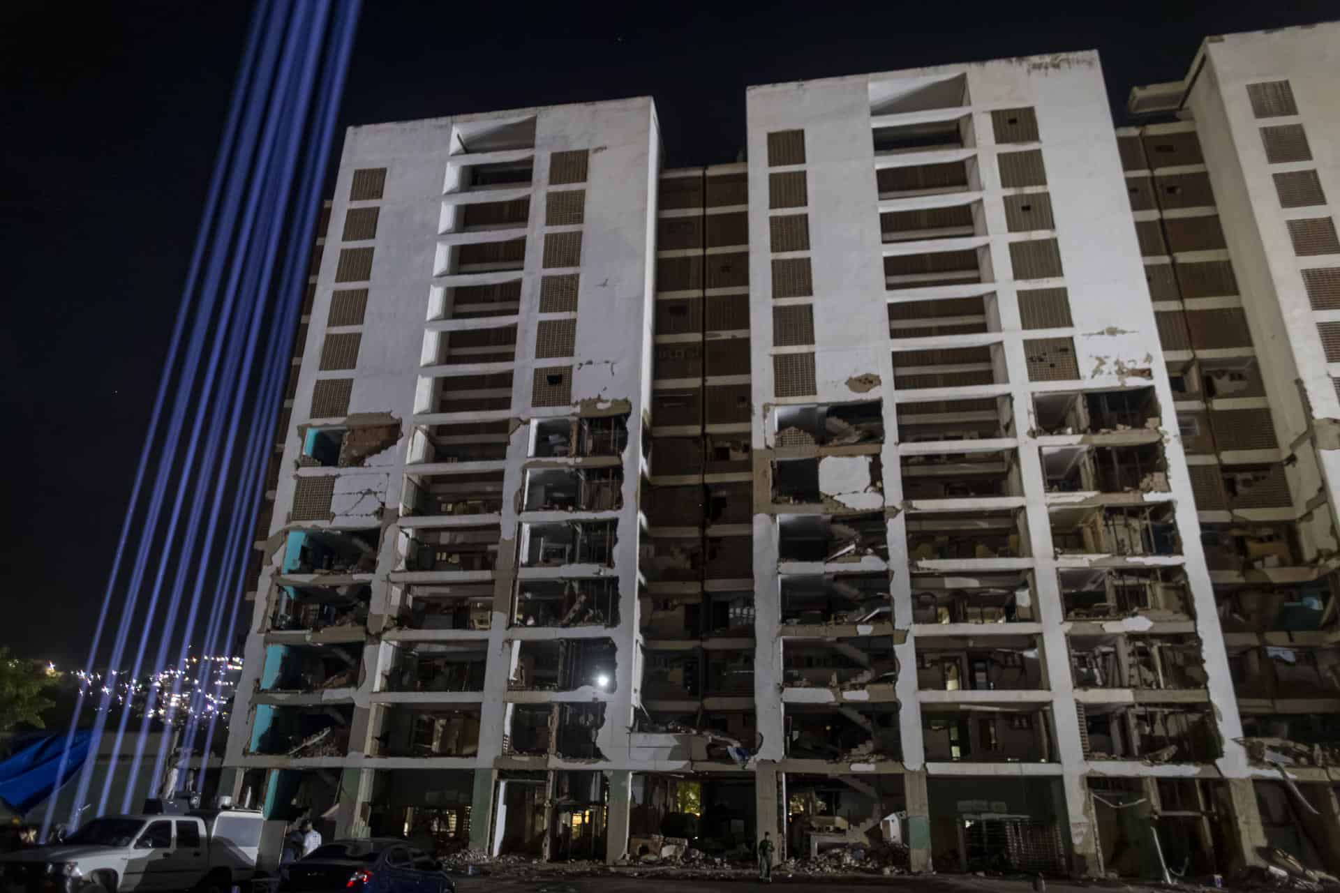 Fotografía que muestra luces proyectadas al cielo junto a un edificio destruido por los terremotos del 24 de junio de 2026 durante un homenaje por los 100 días de la catástrofe que dejó mas de 6500 muertos, este viernes en La Guaira (Venezuela). 
