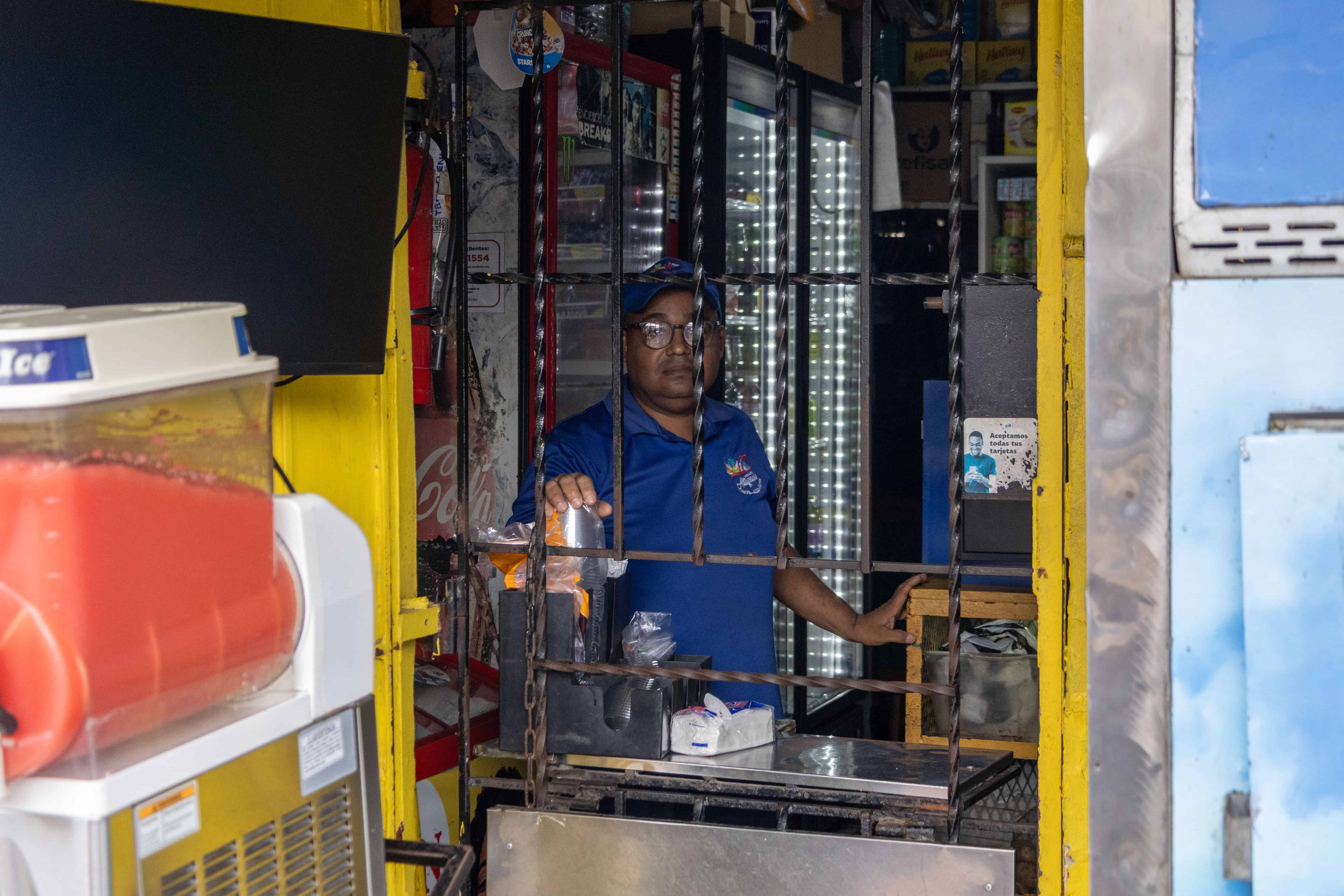 Yeison brinda sus servicios detrás de la verja de su mostrador.