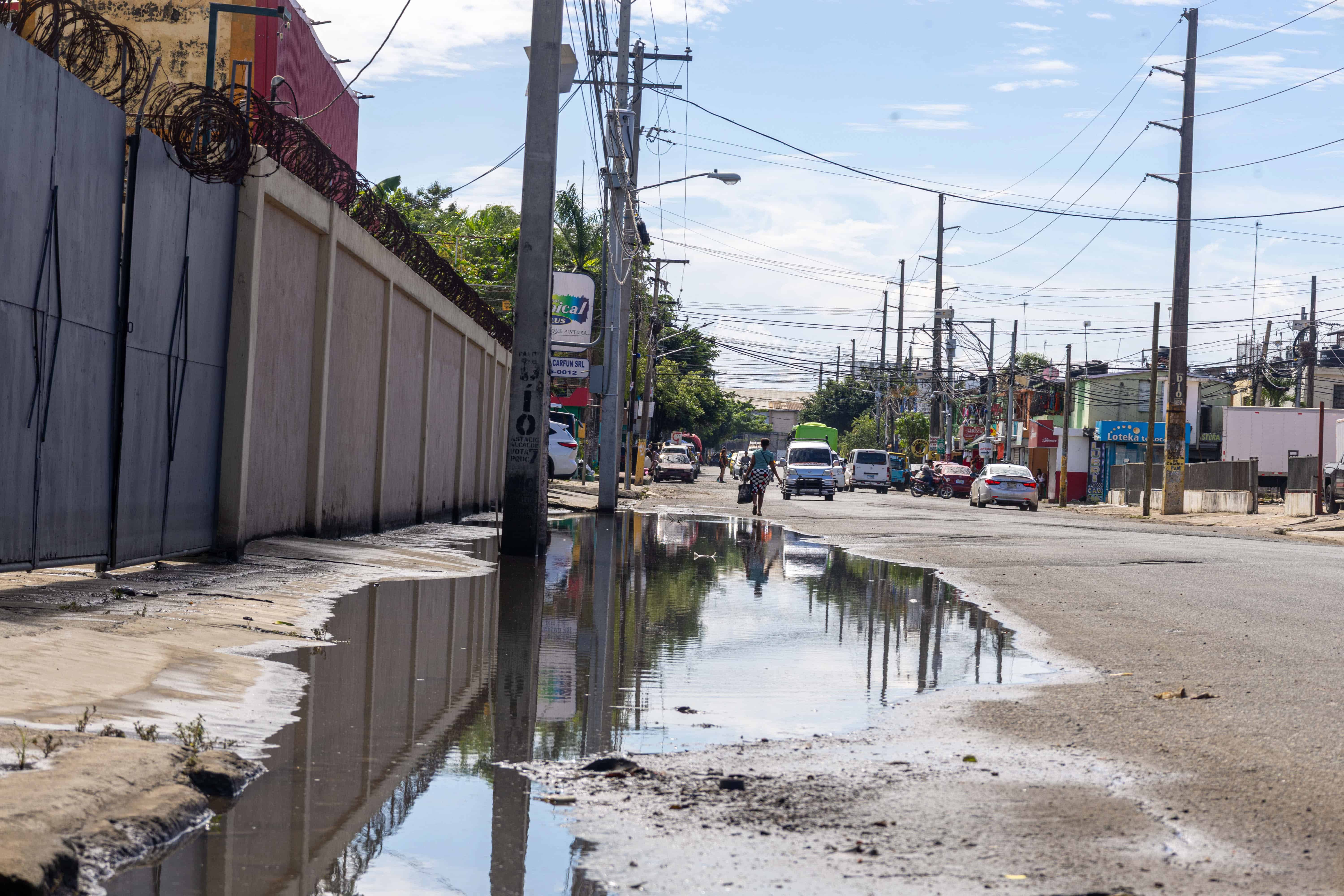 El agua sucia permanecía acumulada en parte de la vía de entrada al sector El Almirante, en Santo Domingo Este, pese a que su nivel había disminuido.